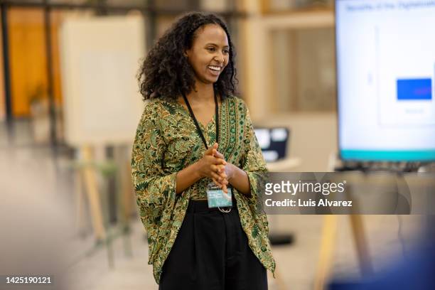 young woman addressing audience during launch event - emcee imagens e fotografias de stock