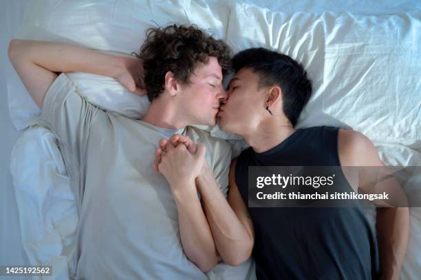 high angle view
affectionate love between gay couple at home kissing in bed. - union gay stockfoto's en -beelden