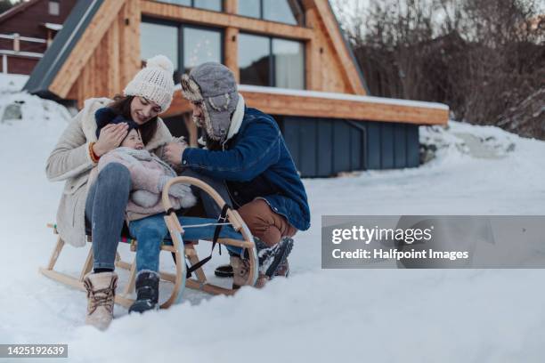 young family enjoying winter, sitting on sled. - family winter sport stock pictures, royalty-free photos & images