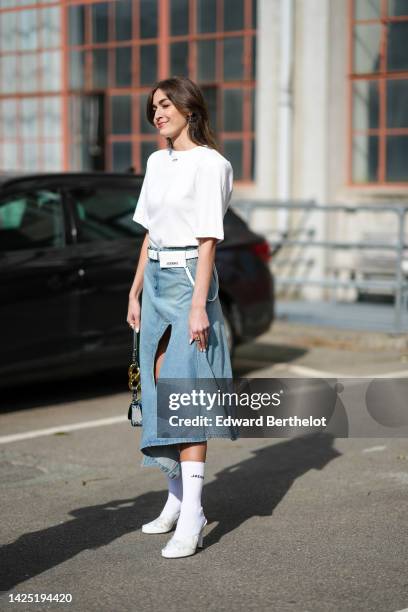 Guest wears silver large logo pendant earrings from JW Anderson, a white short sleeves t-shirt from Off-White, a white matte leather belt bag from...