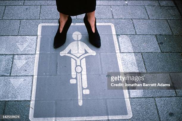 bicycle sign - low section of woman standing in front of arrow sign on road stock pictures, royalty-free photos & images