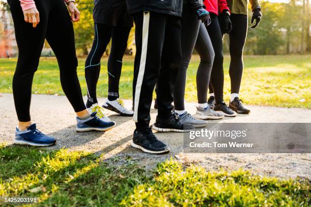 legs and feet of joggers lining up on dirt-track - pantalones negros fotografías e imágenes de stock