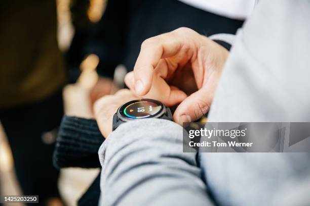 close-up hands of unrecognisable men using smartwatch after exercise, midsection. - smart watch stock pictures, royalty-free photos & images