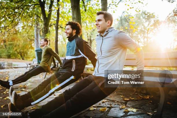 three men doing reverse push-ups on a park bench - crecimiento estirón fotografías e imágenes de stock