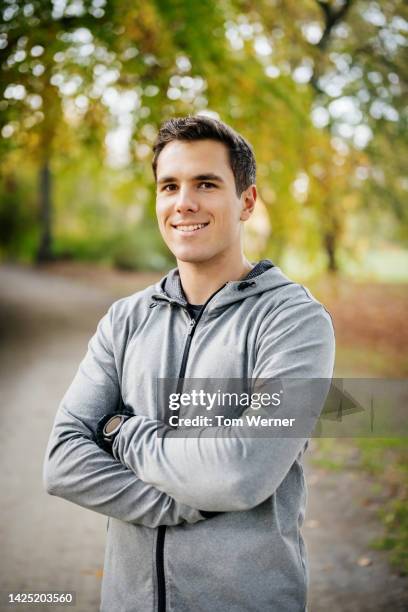 portrait of a young caucasian male runner  with arms crossed - athlete bulges stock pictures, royalty-free photos & images