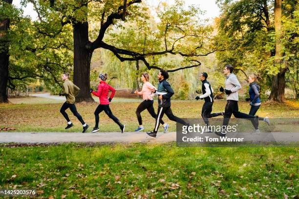 a group of runners racing through the park - after run stock pictures, royalty-free photos & images