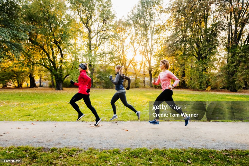 Three caucasian women running through a non-urban area