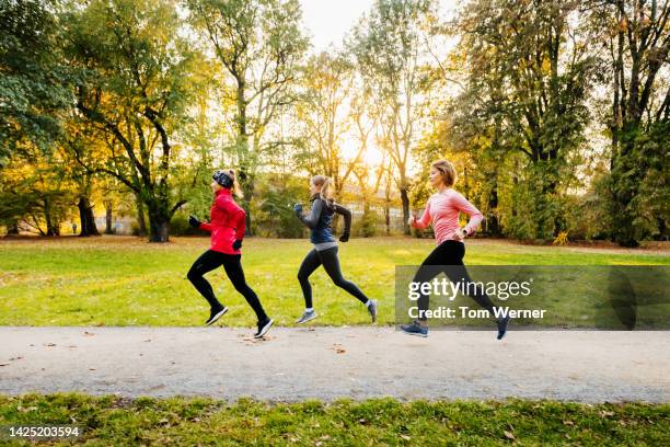 three caucasian  women running through a non-urban area - rennen stockfoto's en -beelden
