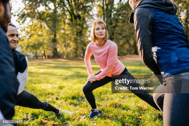 four young active friends stretching together before training. - practice stock-fotos und bilder