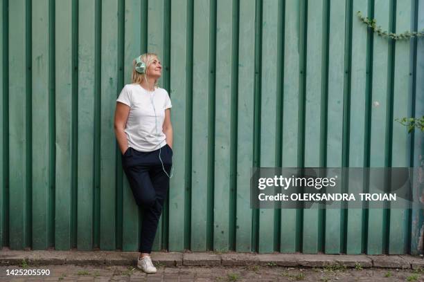 mature blonde woman headshot with green headphones - area 51 stock-fotos und bilder