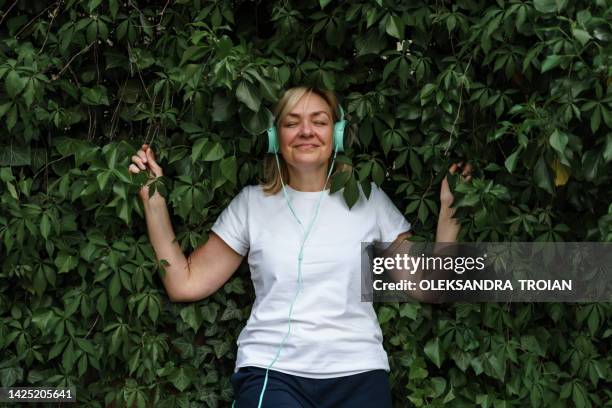 mature woman with headphones in leaves - tshirt template stock pictures, royalty-free photos & images