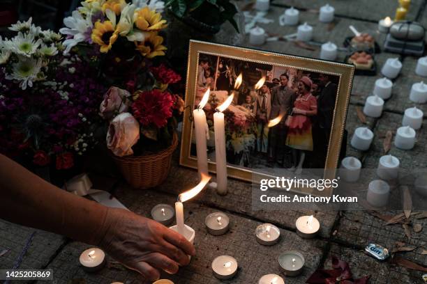 Mourners place candles next to flower tributes for Queen Elizabeth II outside the British Consulate as the world reacts to the passing Of Queen...