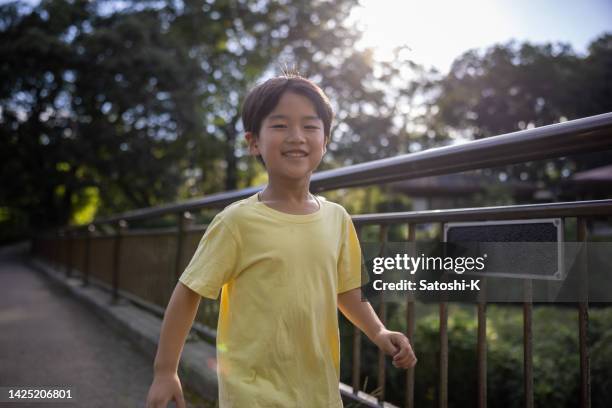 boy walking across the bridge in public park, the sun is shining from the back - teal portrait stockfoto's en -beelden