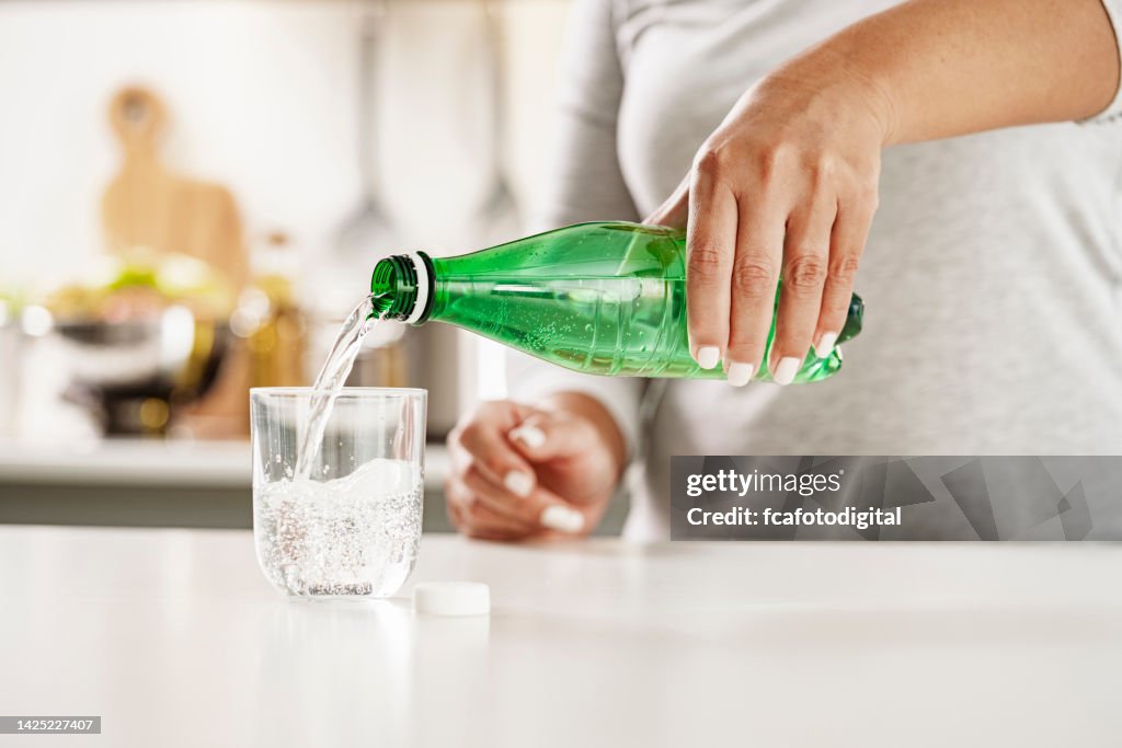 Mineralwasser aus grüner Plastikflasche in Glas gießen