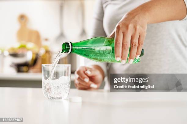 verser de l’eau minérale à partir d’une bouteille en plastique vert dans du verre - soda photos et images de collection