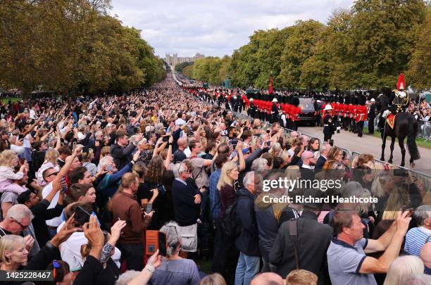 Mourners watch the State Hearse of Queen Elizabeth II as it drives along the Long Walk ahead of the Committal Service for Queen Elizabeth II on...