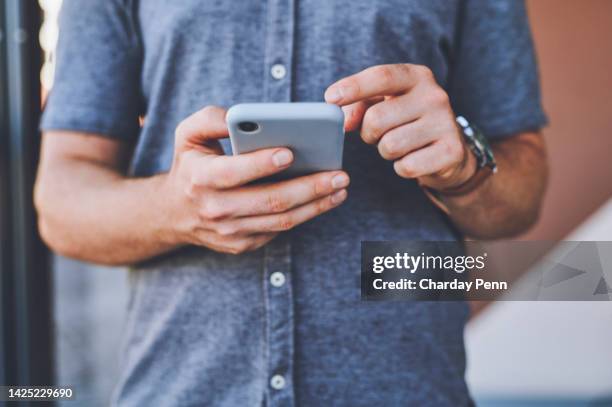 nahaufnahme eines mannes mit den händen eines telefons, der in sozialen medien surft, während er draußen auf der straße der stadt steht. typ, der einen artikel oder blog auf einer website mit einem smartphone in einer städtischen stadtstraße liest. - bloggen stock-fotos und bilder
