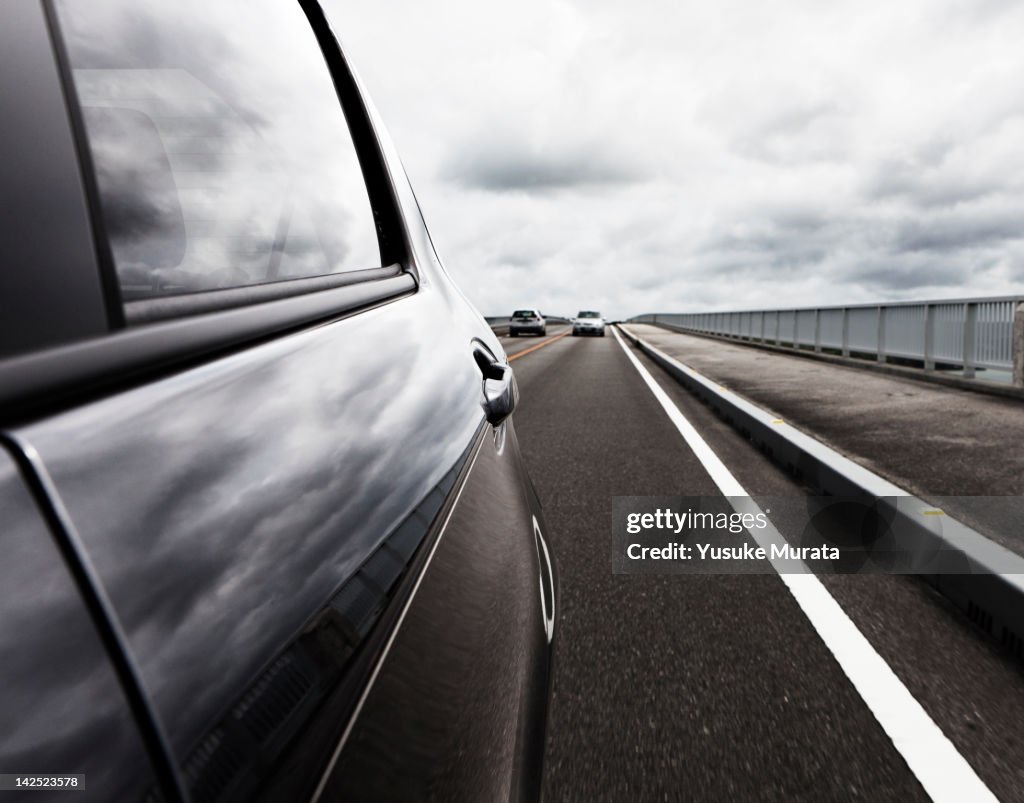 Behind view of car driving along coastal road