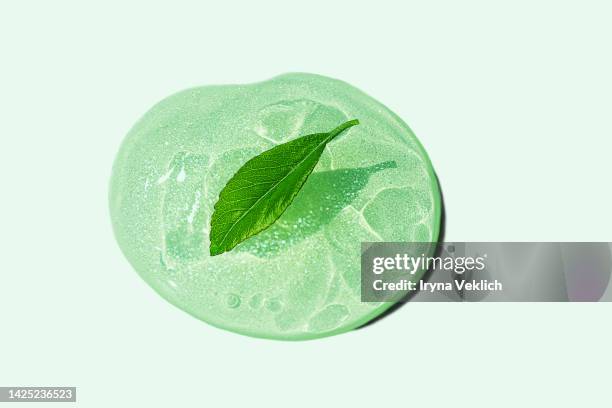 green color smear of gel, face serum or essential oil, shampoo, soap with oxygen aqua bubbles and fresh leaf on green color background. - aloe vera gel stock-fotos und bilder