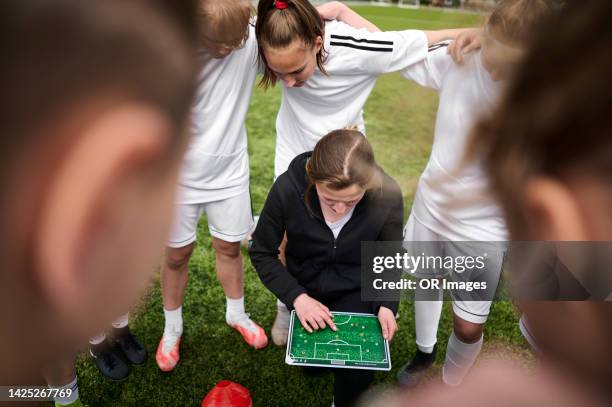 coach with tactics board talking to teenage girl soccer team - sports team huddle stock pictures, royalty-free photos & images