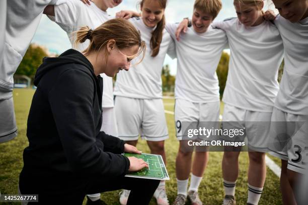 coach with tactics board talking to teenage girl soccer team - huddle sport girls stock pictures, royalty-free photos & images