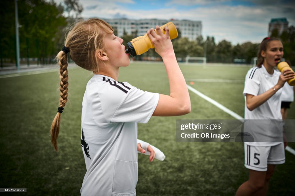 Teenage girl drinking from bottle on soccer field