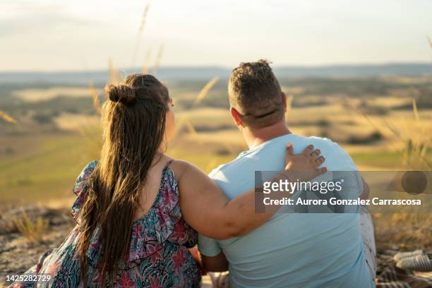 couple in love showing their love on a summer afternoon having a picnic in the field - fat woman stock-fotos und bilder