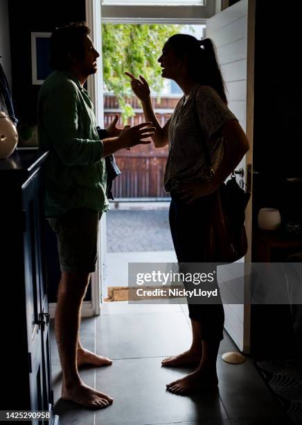 young couple arguing standing at house door - woman walking out door silhouette stock pictures, royalty-free photos & images