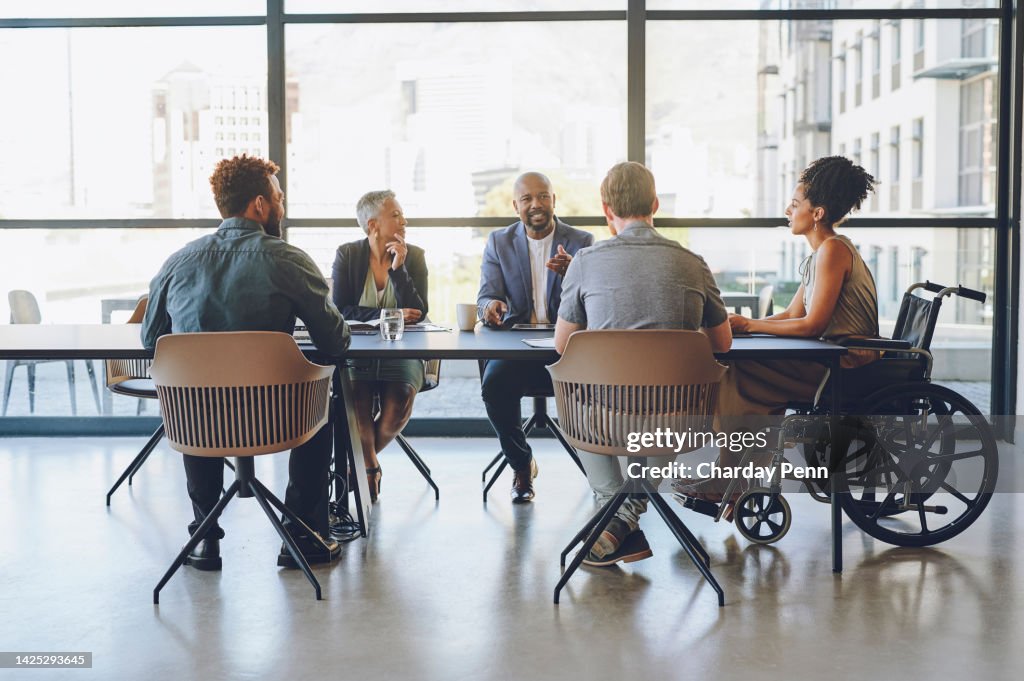 Disability, diversity and business meeting with staff, people or team communication, planning on corporate strategy, goal or mission for KPI. Woman in wheelchair in group talking of company inclusion