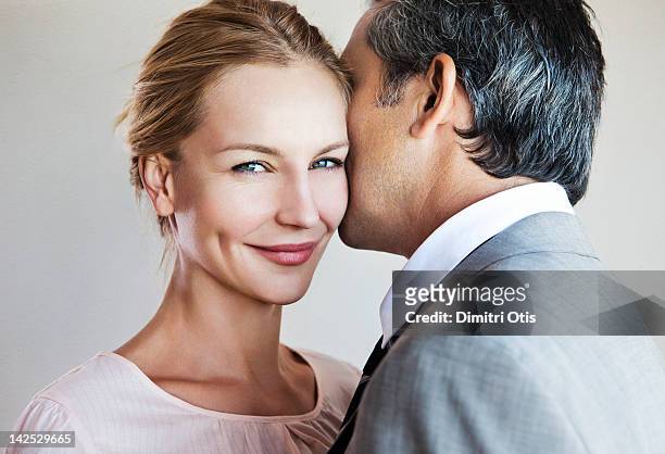 man whispering to smiling woman - coppia eterosessuale foto e immagini stock