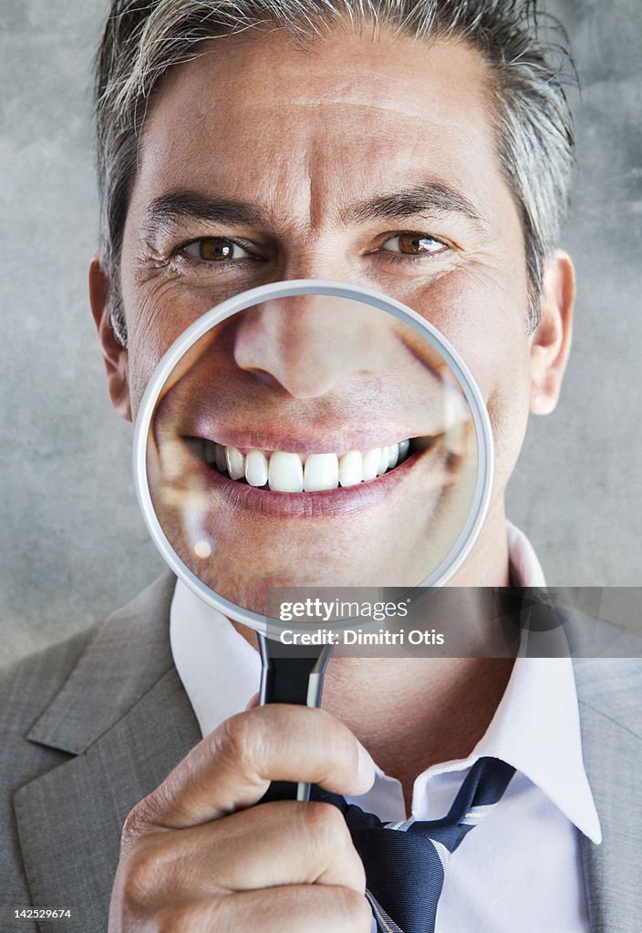 Man's smile enlarged in magnifying glass