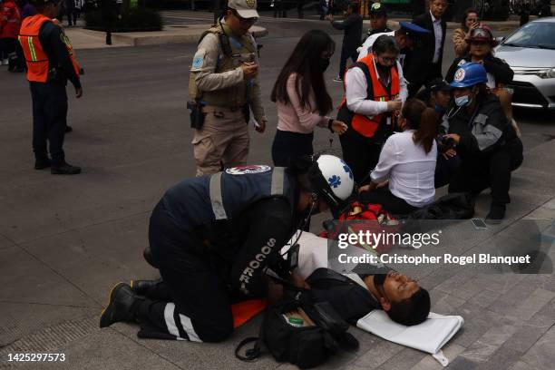 Paramedic assists a man after a 7.7 magnitude quake that struck the west coast in Michoacan State, was felt in Mexico City right after a drill to...