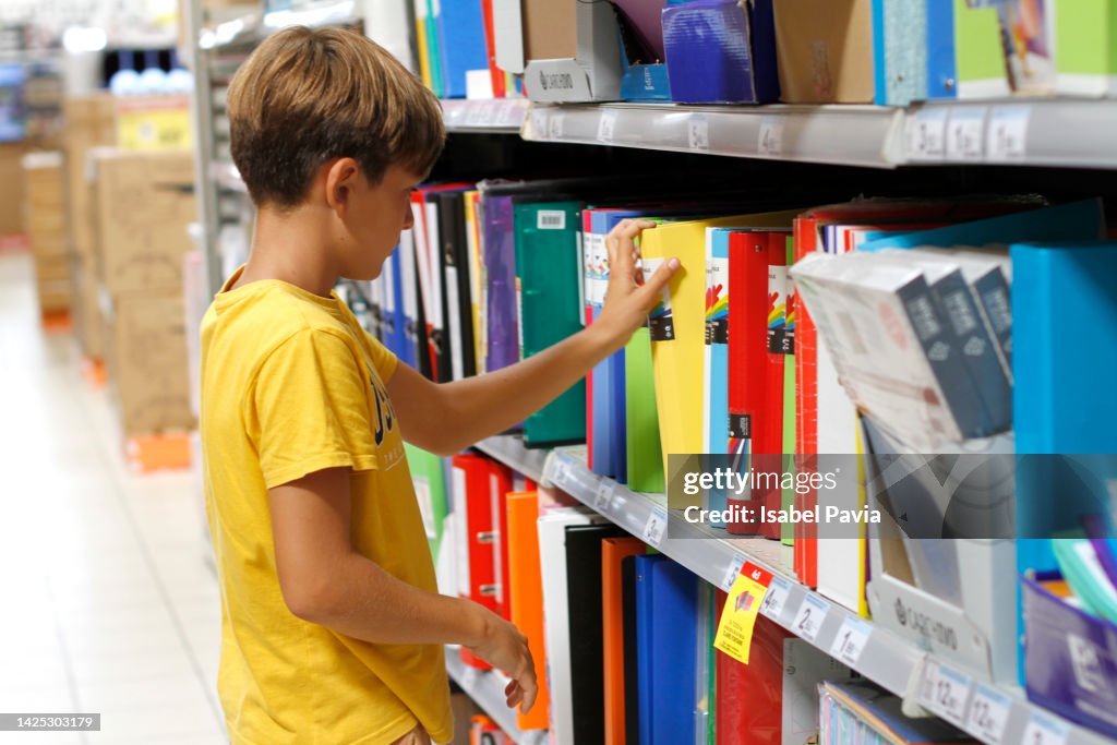Boy looking notebooks on the bookshelf at the stationery shop