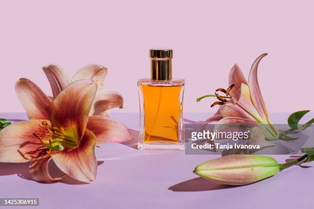 bottle of perfume with lily flowers on purple background. beauty products for body and face care. minimal style perfumery template - 香水 個照片及圖片檔