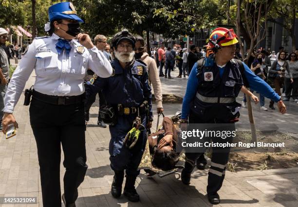 Rescuers carry a person on a stretcher after a 7.7 magnitude quake that struck the west coast in Michoacan State, was felt in Mexico City right after...