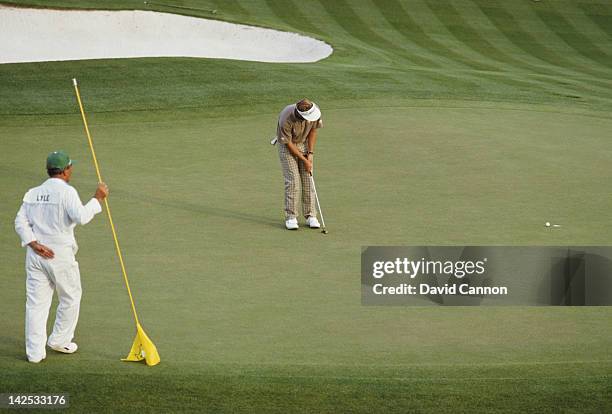 Caddy Dave Musgrove looks on as Sandy Lyle of Great Britain holes out his putt on the final 18th hole to win the US Masters Golf Tournament on 10th...
