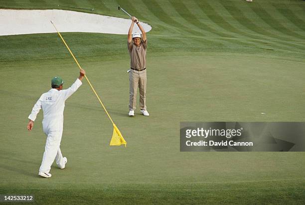 Caddy Dave Musgrove looks on as Sandy Lyle of Great Britain holes out his putt on the final 18th hole to win the US Masters Golf Tournament on 10th...