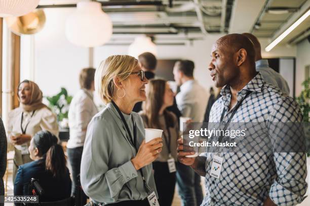 mature businesswoman talking with male colleagues in break at convention center - disposable cup stock pictures, royalty-free photos & images