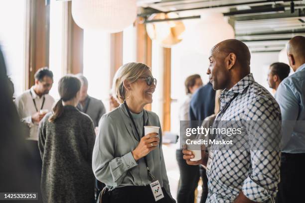 smiling mature businesswoman talking with male colleagues in break at convention center - business conference - fotografias e filmes do acervo