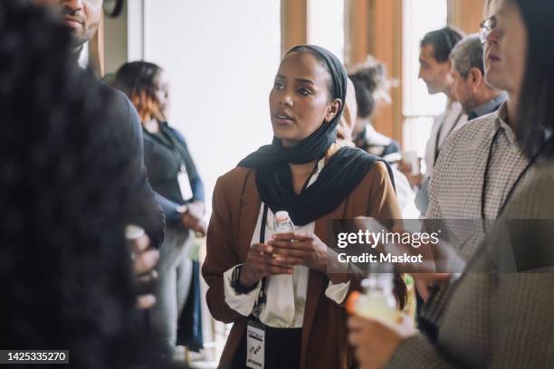 business colleagues discussing during break time in convention center - arab group stockfoto's en -beelden