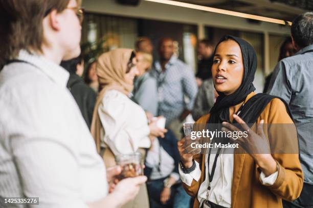 young businesswoman discussing with male colleague in break at convention center - woman headscarf stock pictures, royalty-free photos & images