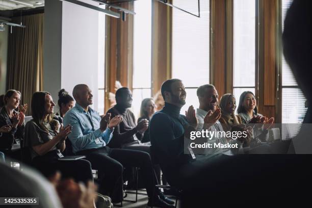 happy multiracial business colleagues applauding during meeting in convention center - panel discussion stock pictures, royalty-free photos & images