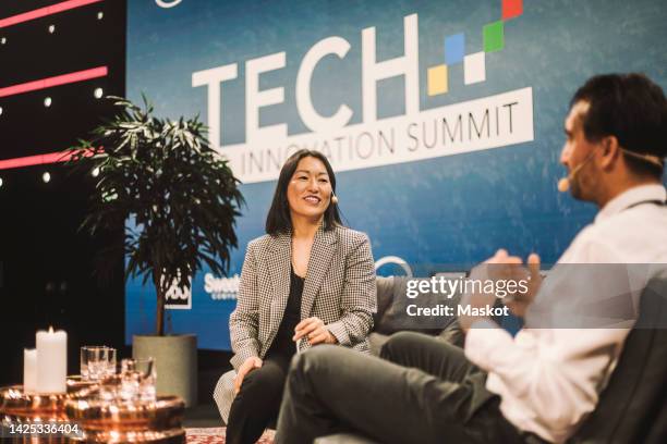 smiling interviewer interacting with tech entrepreneur during panel discussion at conference event - panel discussion stock pictures, royalty-free photos & images