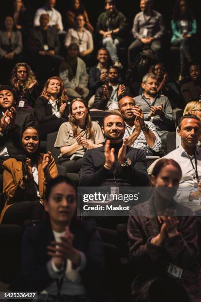 happy multiracial business colleagues applauding in conference event at convention center - conference center stockfoto's en -beelden