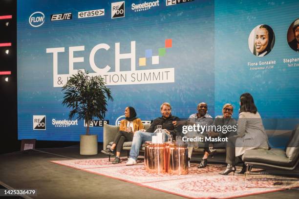 female interviewer talking with tech entrepreneurs during panel discussion at conference event - panel discussion stock pictures, royalty-free photos & images