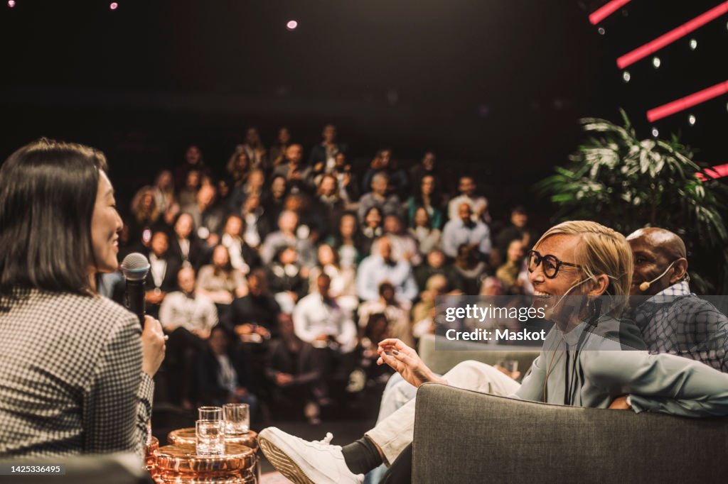 Interviewer interacting with smiling entrepreneurs during panel discussion at conference event