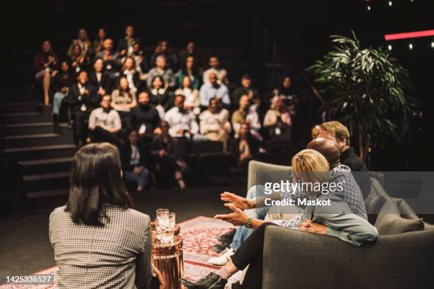 tech entrepreneurs talking by interviewer during panel discussion at convention center - interview event stock pictures, royalty-free photos & images