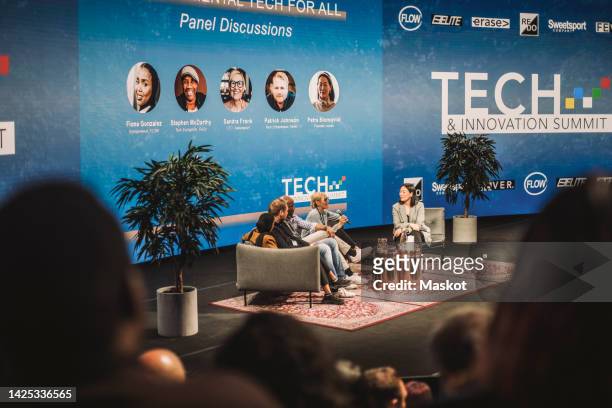 multiracial tech entrepreneurs interacting with interviewer during panel at conference event - women podium stock-fotos und bilder