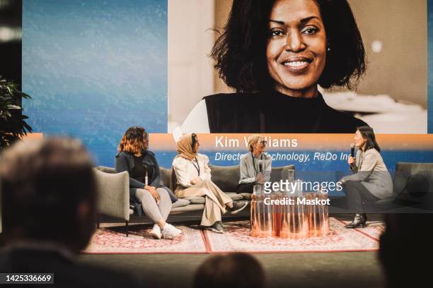 interviewer talking with female tech entrepreneurs during panel at conference event - women podium stock-fotos und bilder