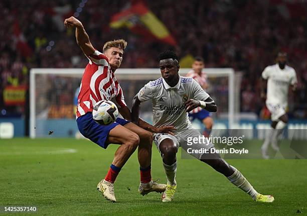 Marcos Llorente of Atletico de Madrid is challenged by Vinicius Junior of Real Madrid goes for a high ball against during the LaLiga Santander match...